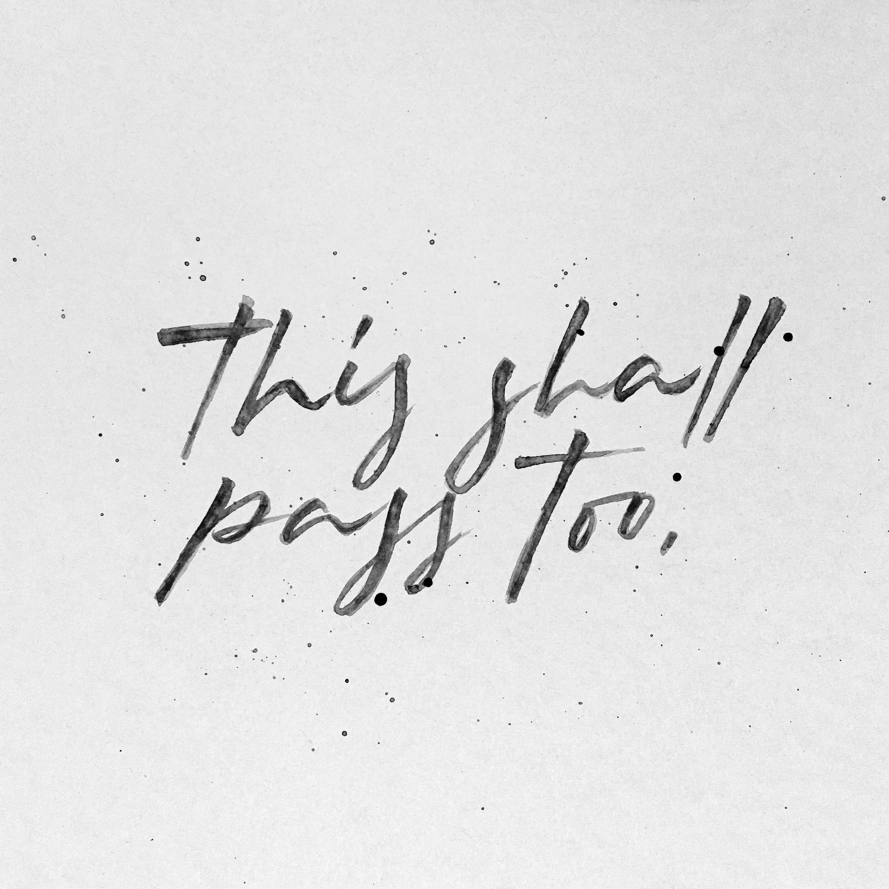 Black ink calligraphy reading This shall pass too on textured paper with expressive ink splatters
