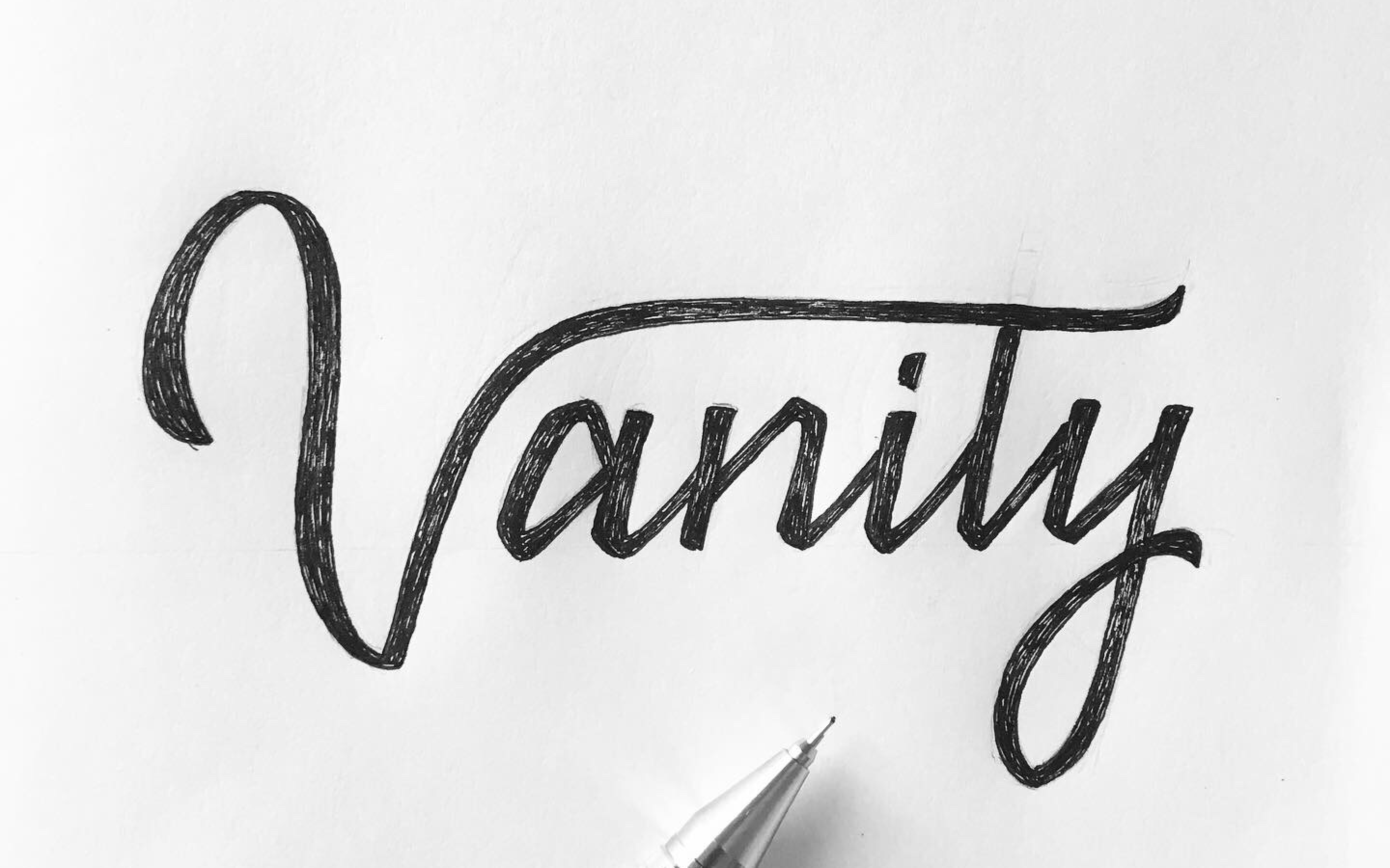 Hand-lettered word Vanity in cross-hatched cursive with a mechanical pencil tip visible at the bottom