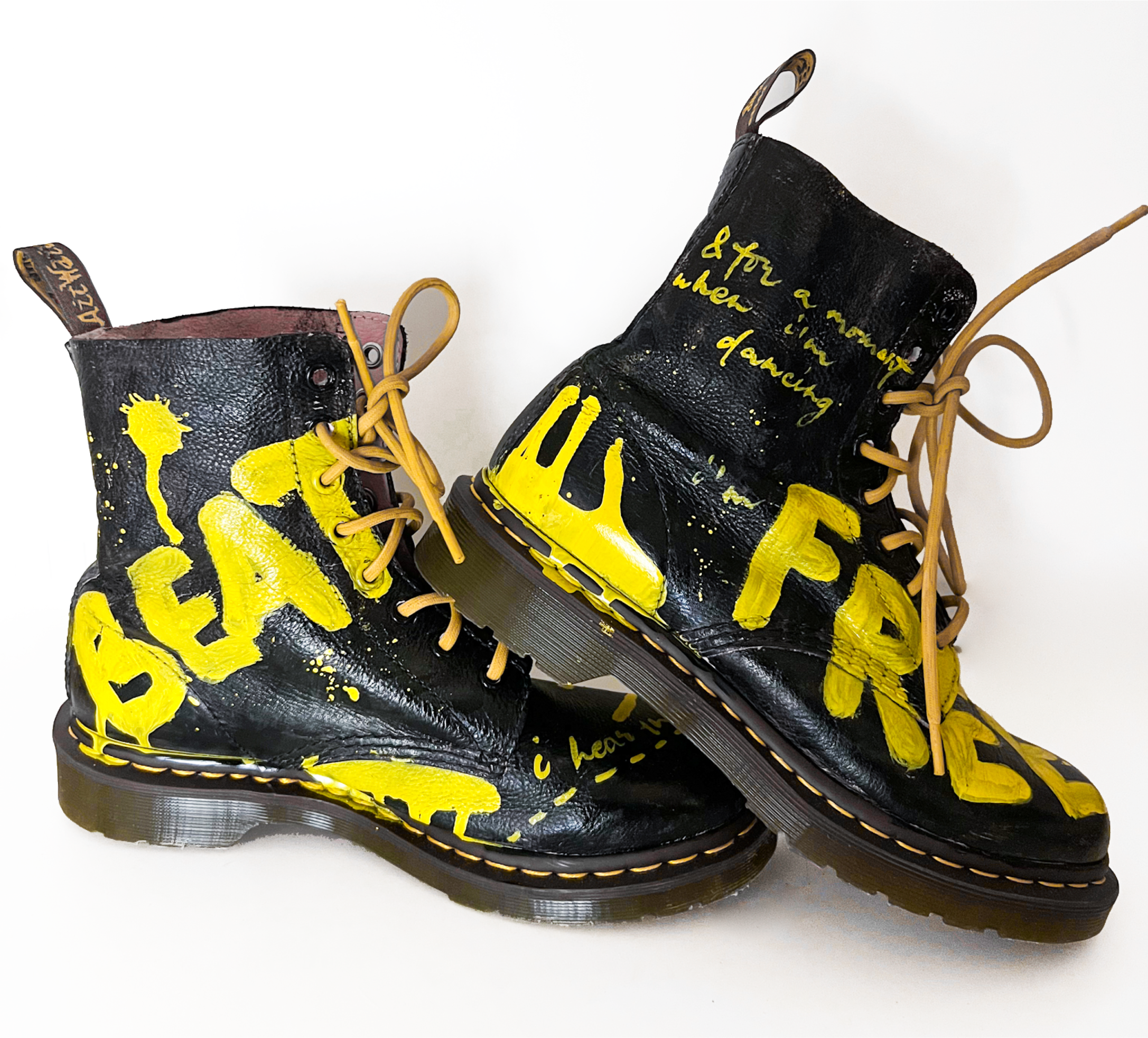 Custom black Dr. Martens boots painted with BEAT and FREE in yellow with handwritten lyrics about dancing
