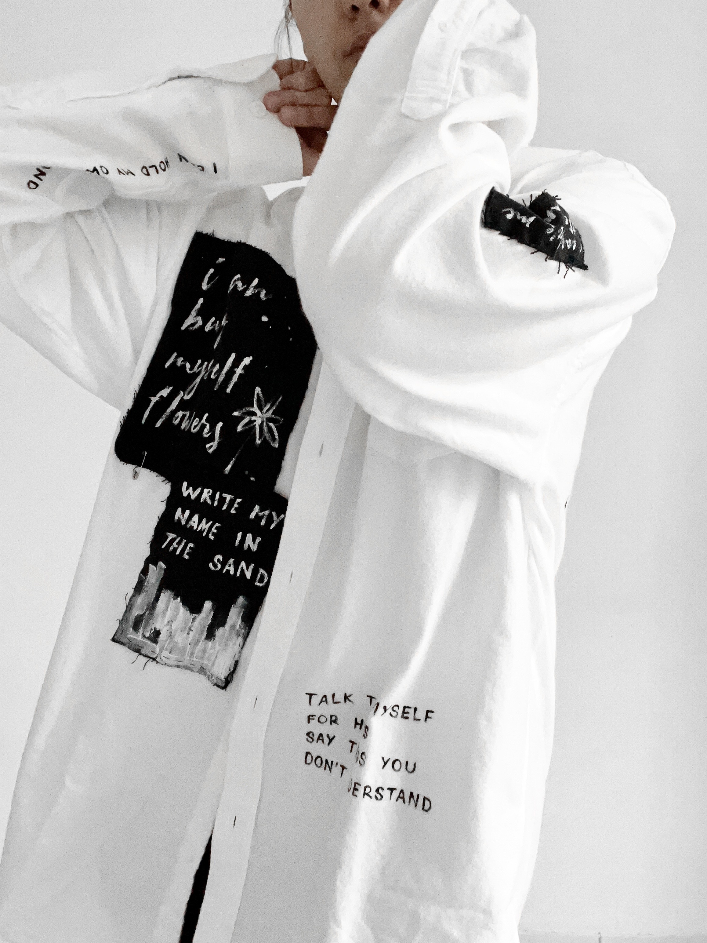 Custom white shirt with black fabric patches reading I can buy myself flowers and handwritten lyric-inspired text